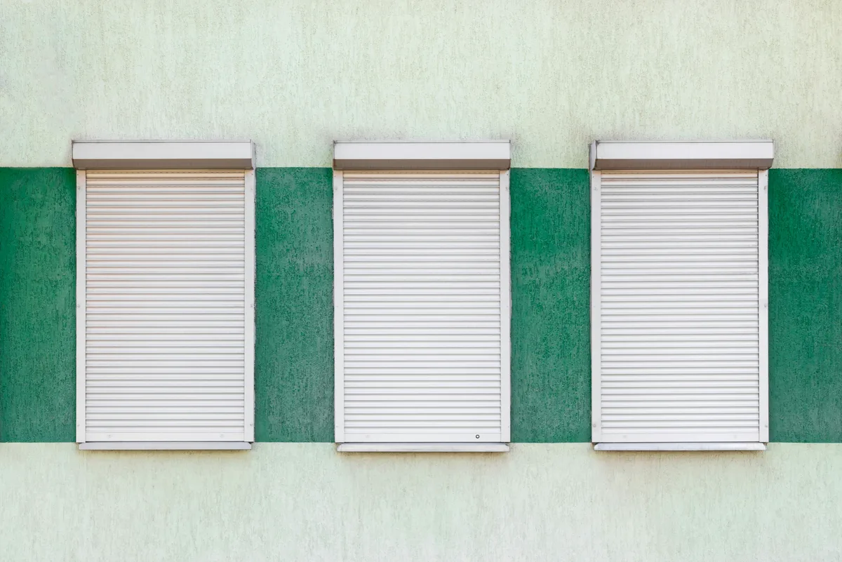 Weiße Rollladen mit Aufsatzkästen an drei Fenstern einer Fassade in Offenburg